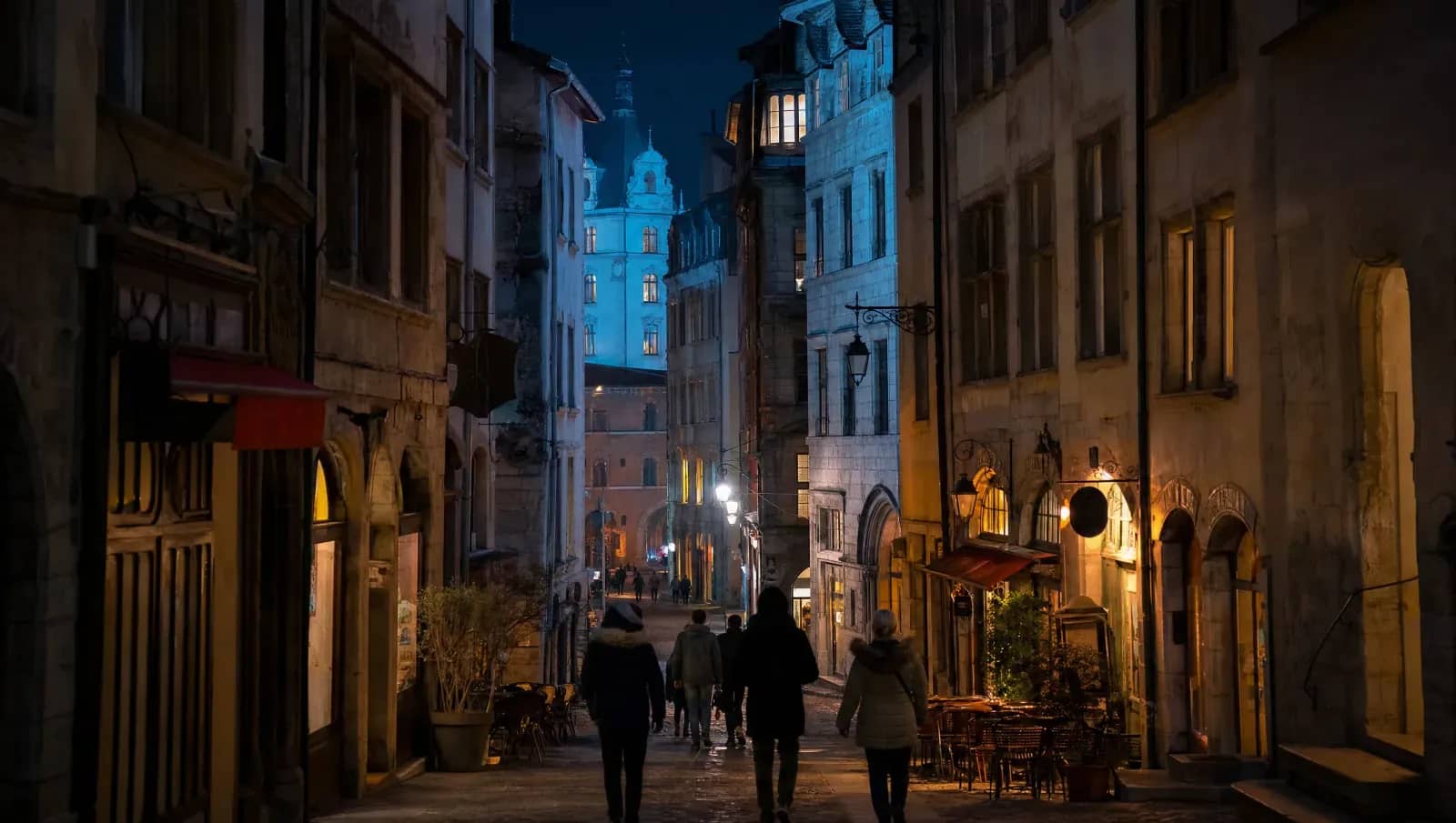 Une rue Renaissance du Vieux Lyon la nuit en décembre, avec les devantures éclairées des restaurants