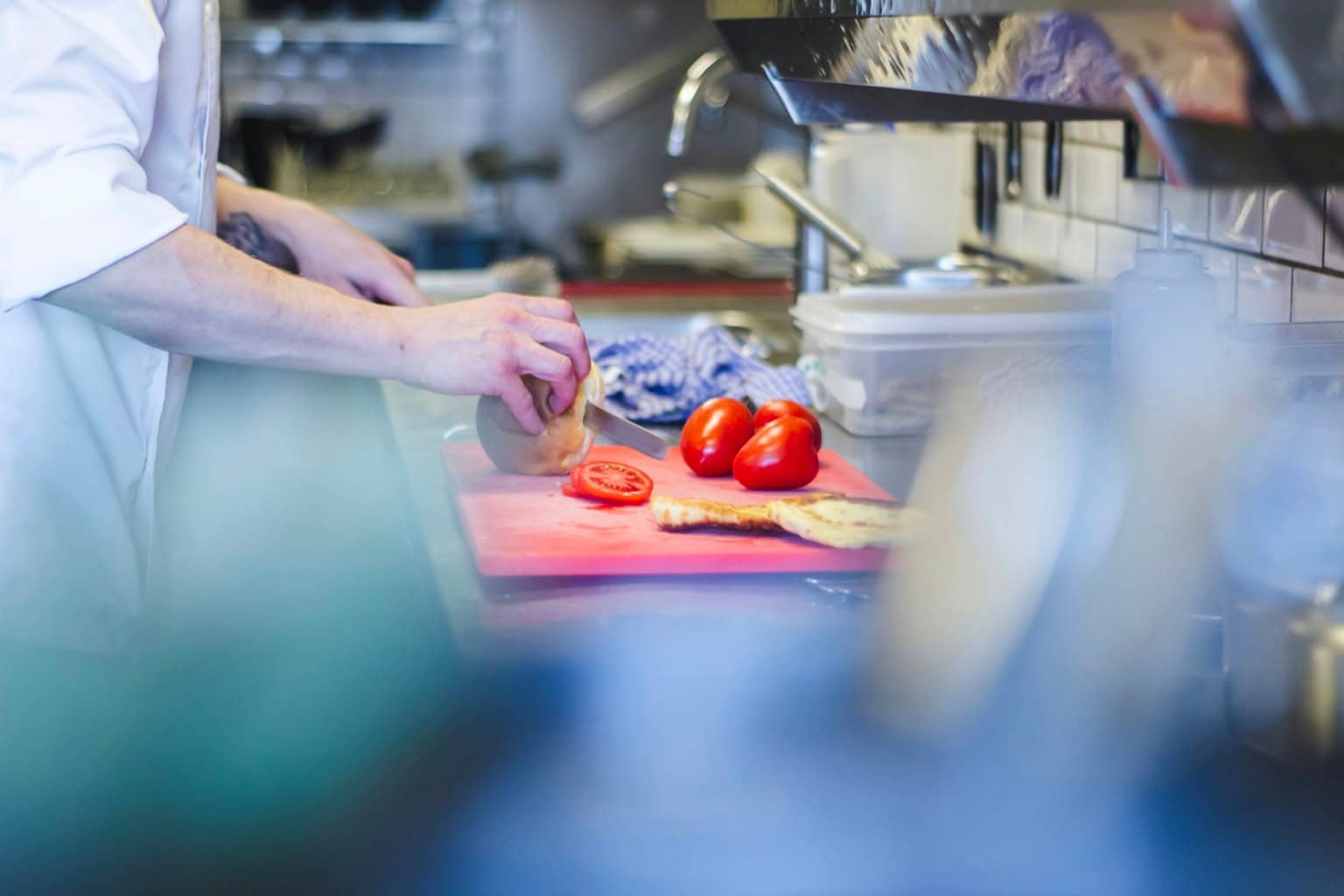 Cuisinier coupant des tomates fraîches en cuisine professionnelle