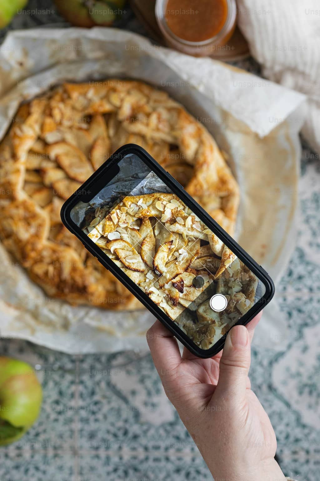 Photographe capturant une tarte au smartphone en lumière naturelle