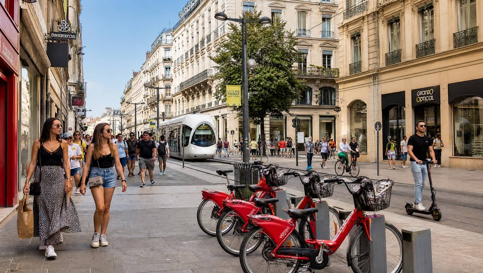 Rue piétonne animée de la Presqu'île à Lyon avec tram, vélos et trottinettes