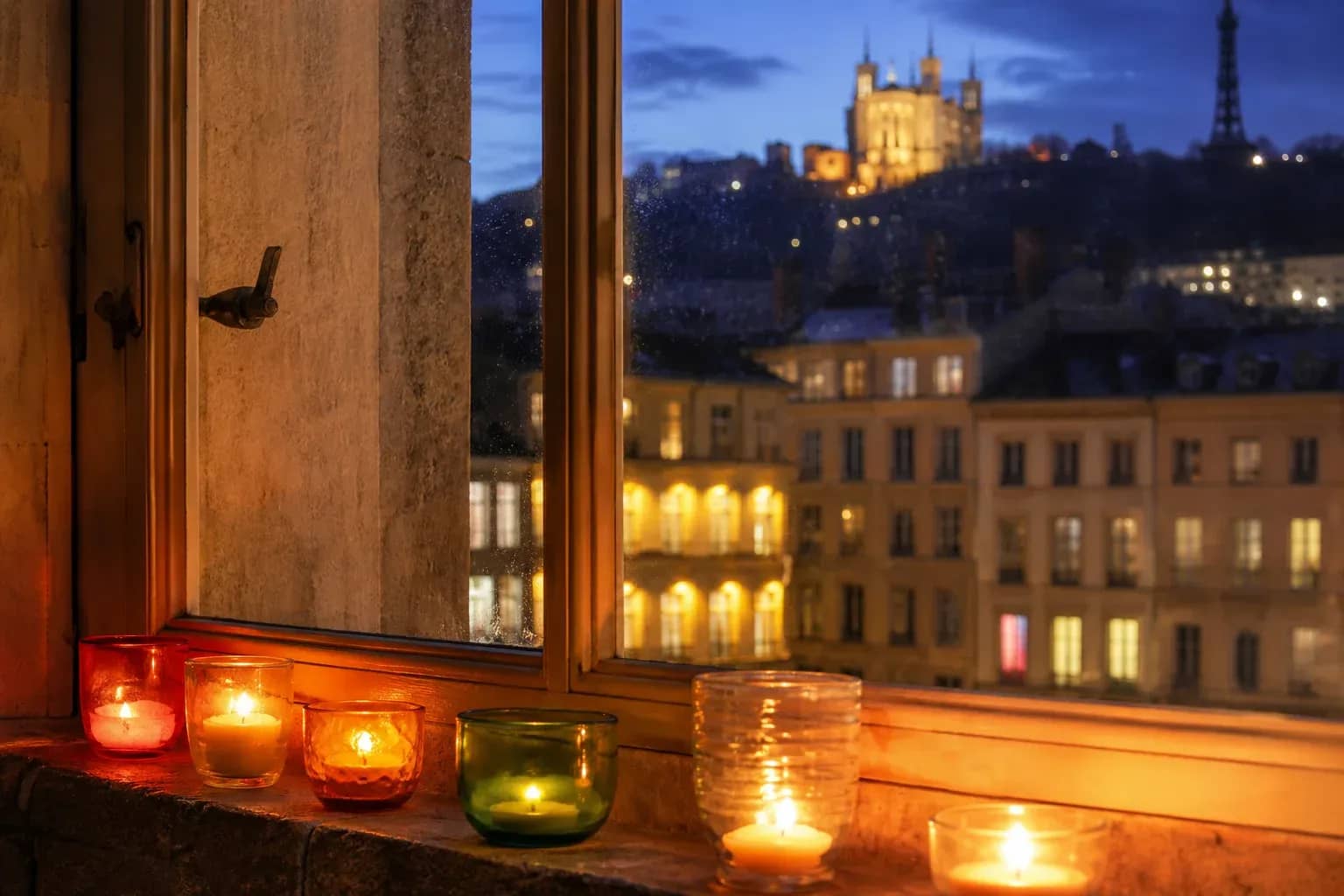 Lumignons colorés allumés sur une fenêtre lyonnaise face à Fourvière