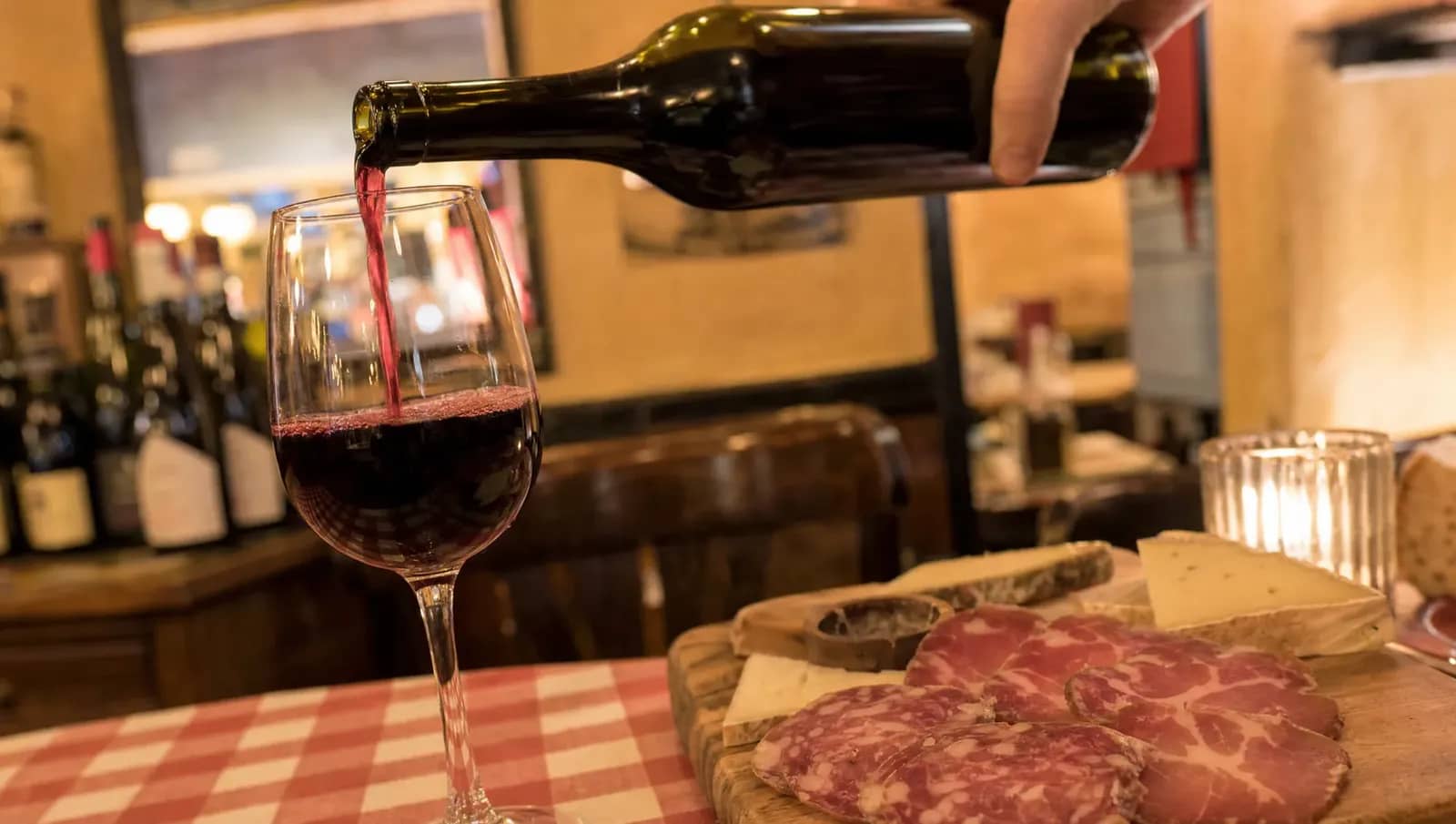 Service d'un verre de Beaujolais Nouveau au-dessus d'une planche de charcuterie et de fromages dans un bouchon lyonnais