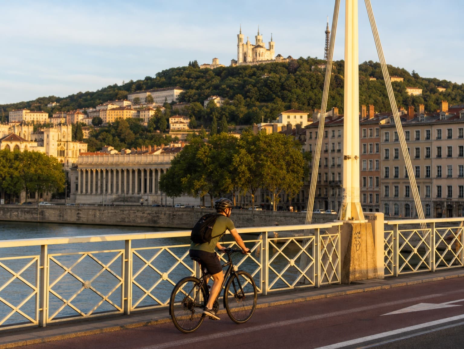 Cycliste traversant un pont sur la Saône avec Fourvière en arrière-plan