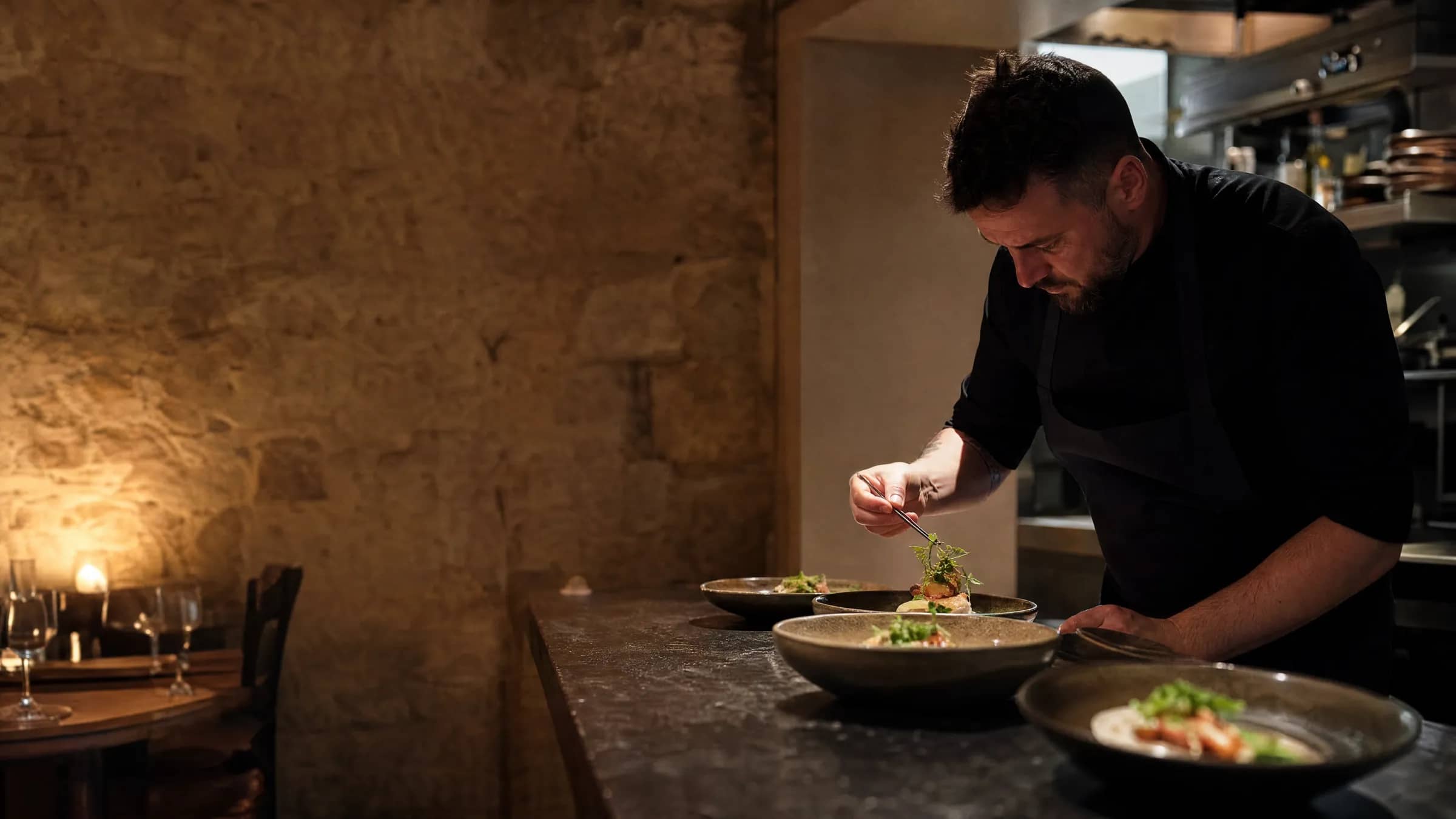 Chef-propriétaire d'un restaurant indépendant lyonnais dressant une assiette dans sa cuisine ouverte, illustrant une alternative locale à Guestonline