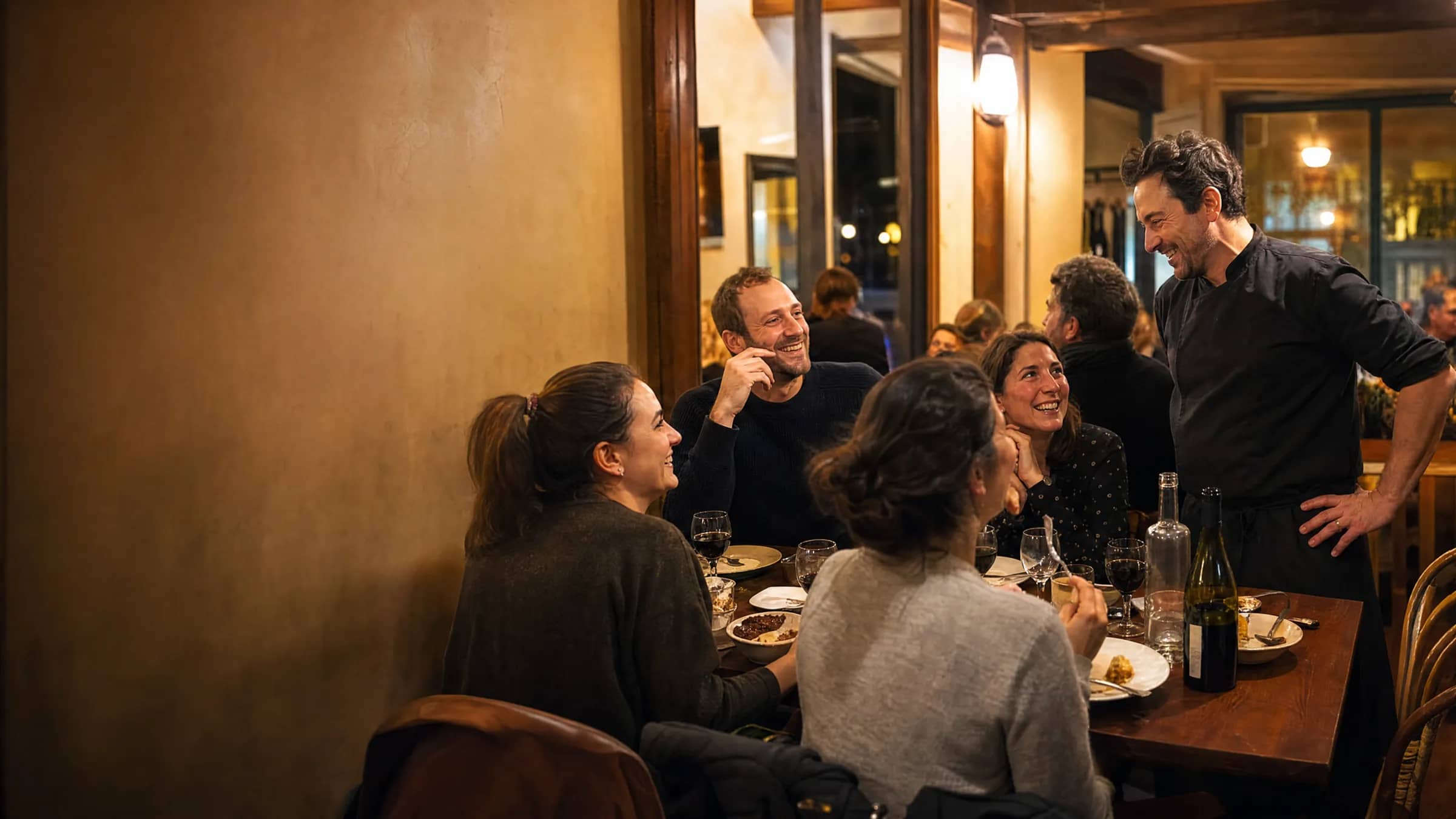 Une table de dîneurs lyonnais profite d'un dîner servi par le patron dans un bistrot indépendant de la Presqu'île, illustrant une alternative à Reservio pensée pour la restauration