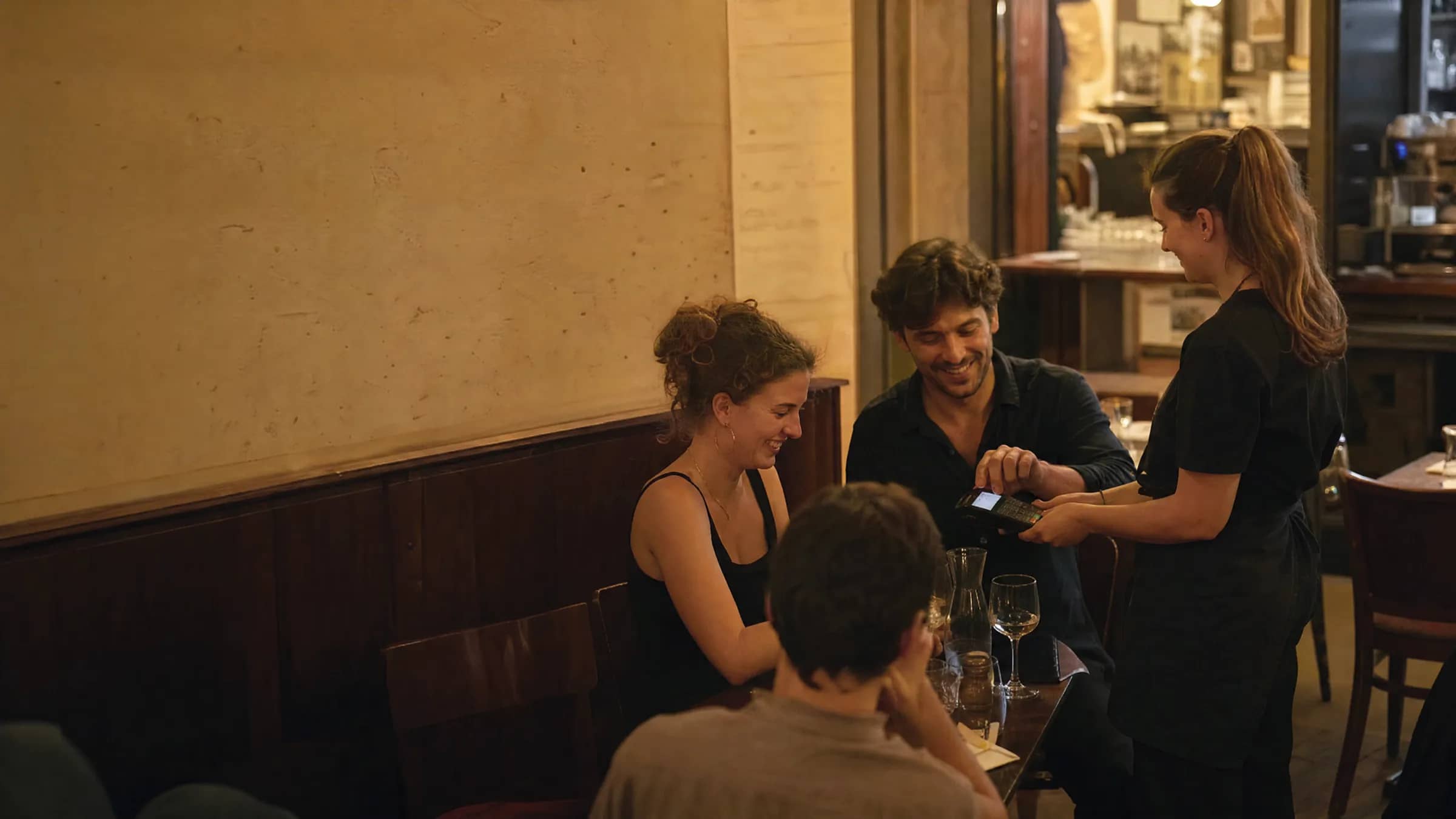 Des clients règlent l'addition en fin de repas dans un bistrot lyonnais chaleureux, illustrant la complémentarité entre encaisser vite avec Sunday et remplir les tables avec TheGoodSeat.