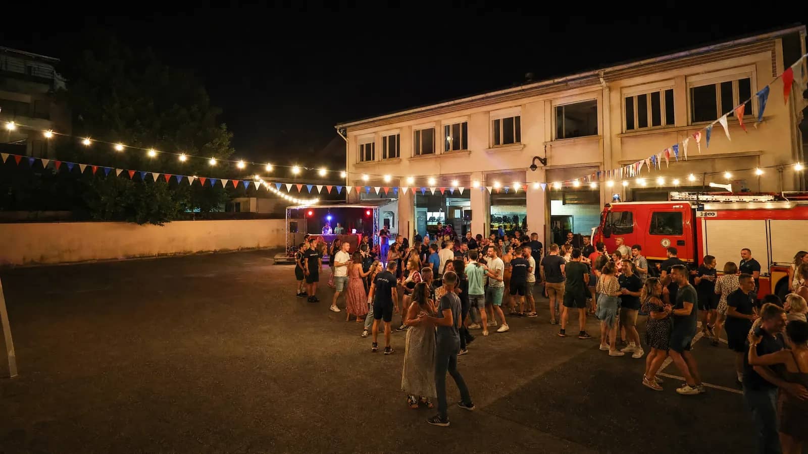 Bal des pompiers dans la cour d'une caserne lyonnaise, guirlandes et fanions tricolores