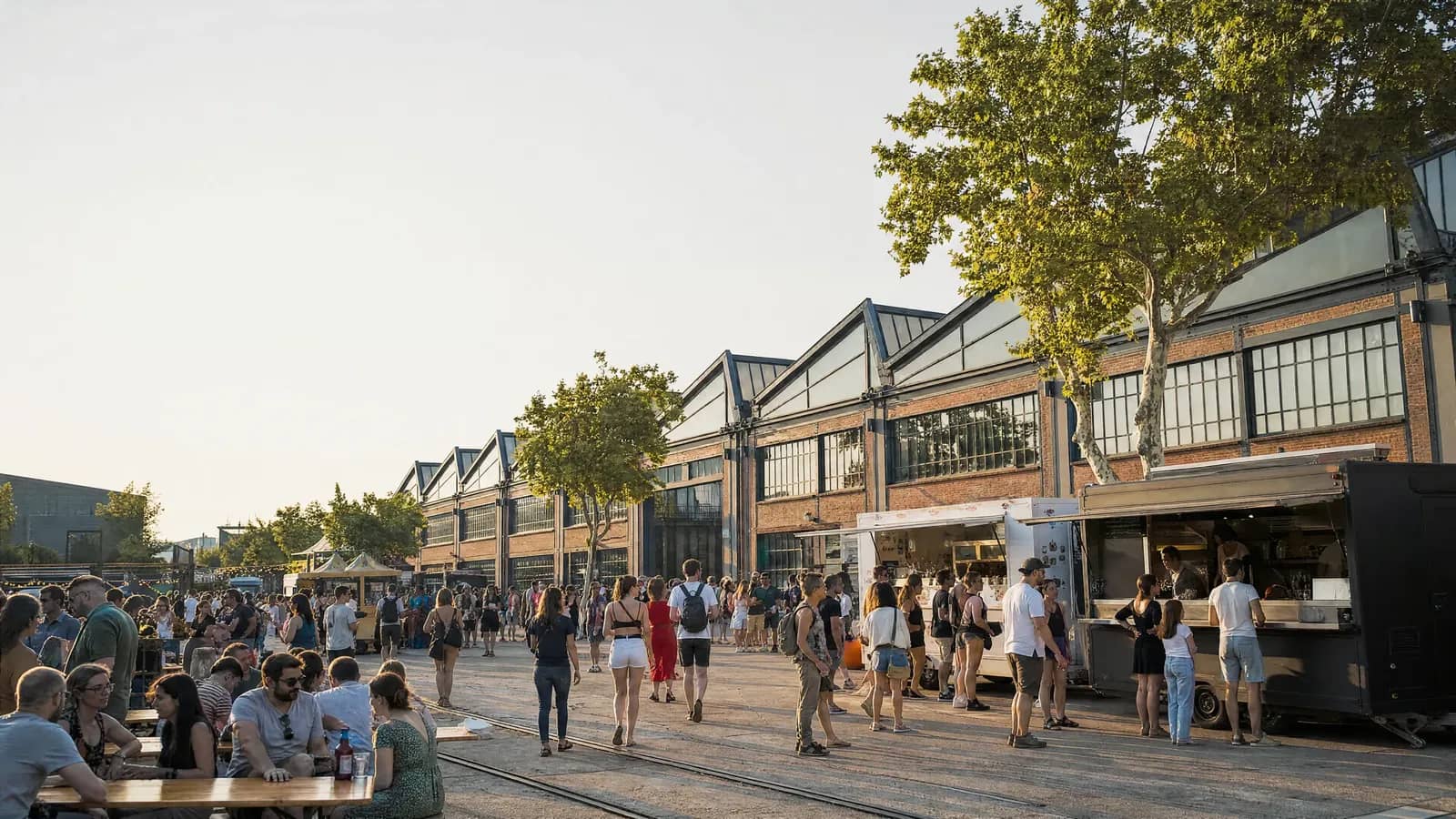 Foule, food trucks et tablées sur l'esplanade des Grandes Locos, devant les anciennes halles ferroviaires à sheds, pendant le Lyon Street Food Festival.