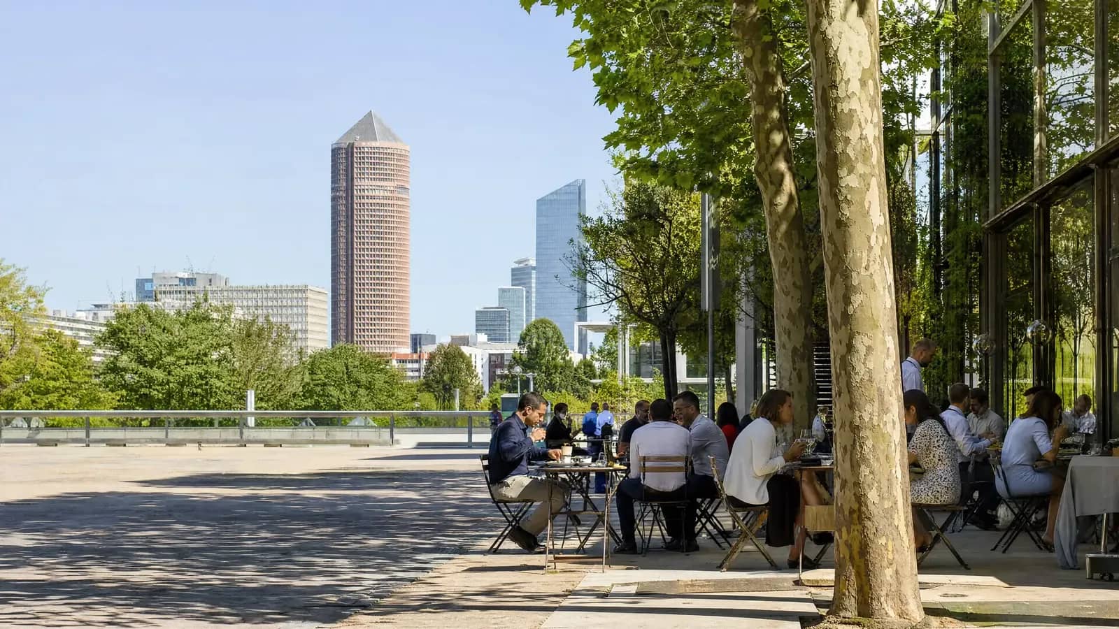 Terrasse de café à l'heure du déjeuner dans le quartier de la Part-Dieu à Lyon, avec la tour Part-Dieu en arrière-plan