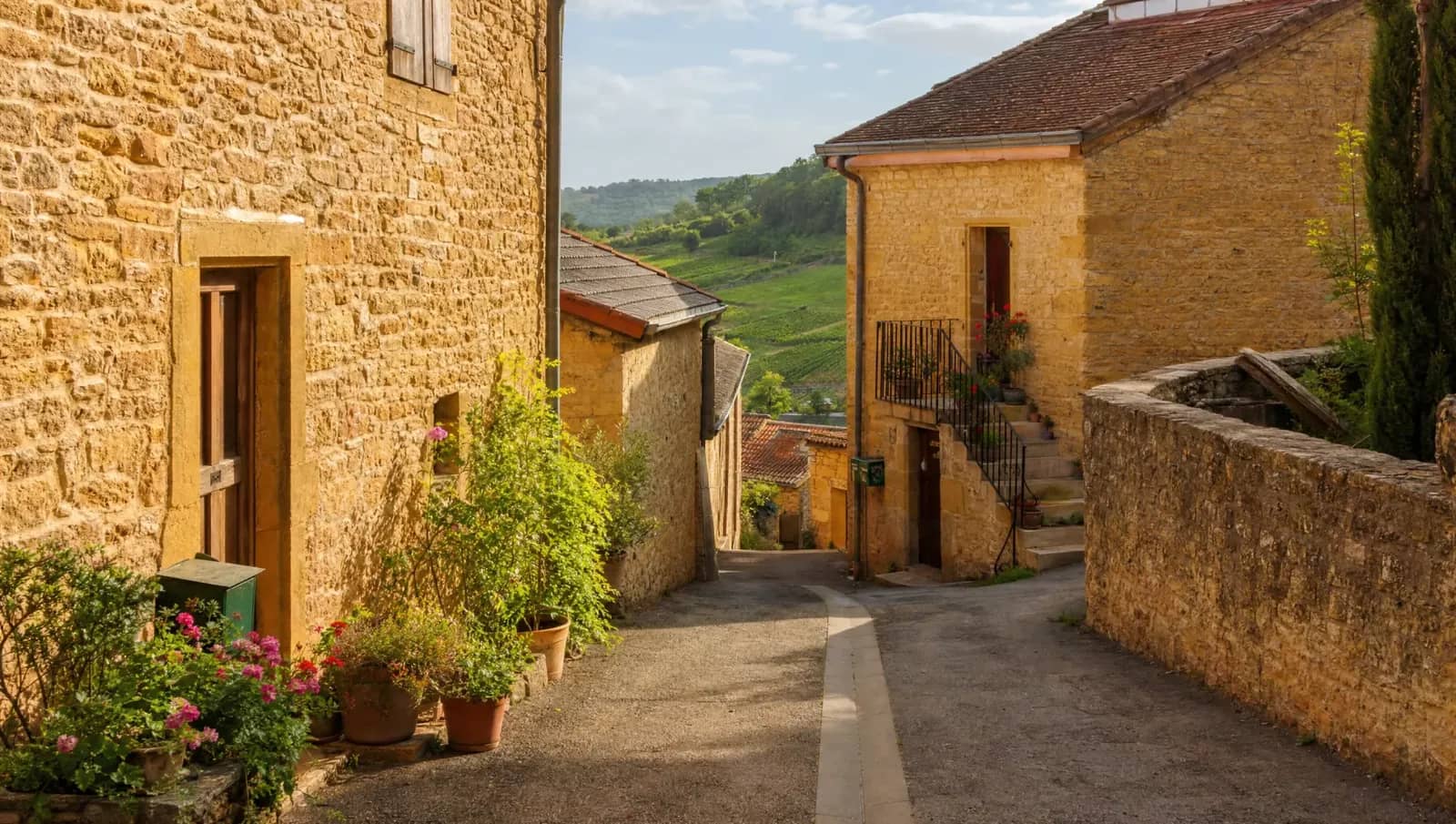 Ruelle d'un village du Beaujolais des Pierres Dorées, façades en calcaire ocre-jaune et vignes en contrebas