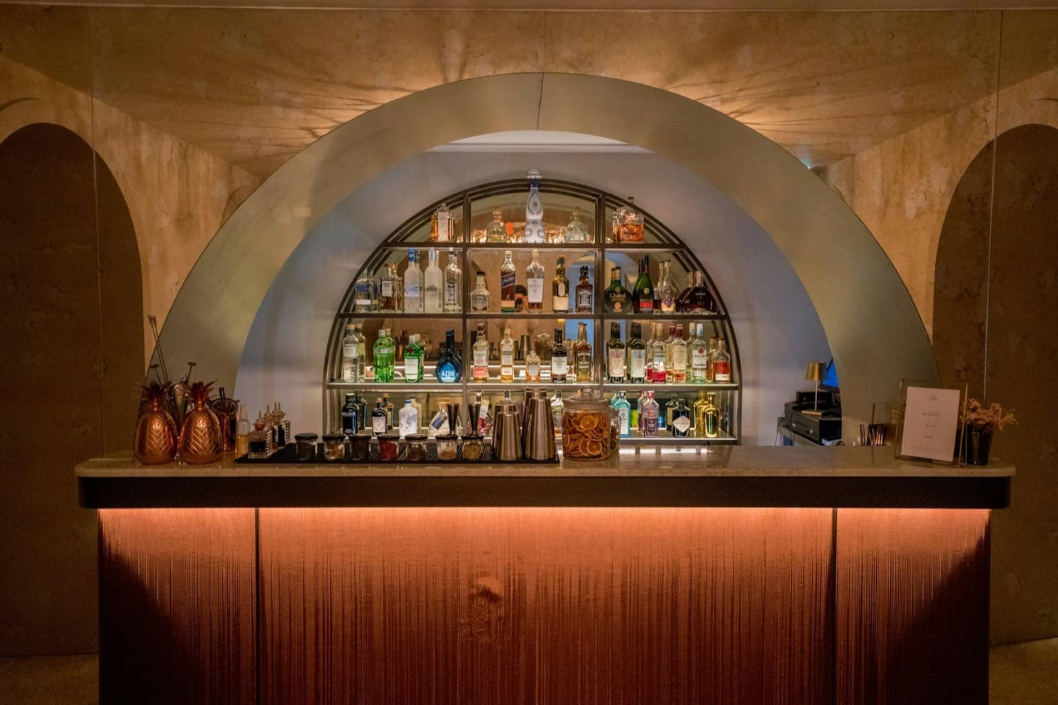 Bar à cocktails en soirée, étagères illuminées de bouteilles