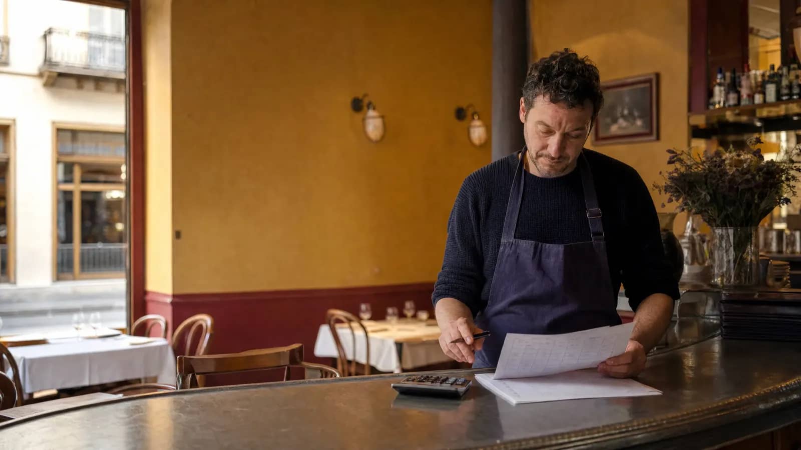 Un restaurateur lyonnais vérifie le planning et les coûts de son équipe au comptoir en zinc de son bistrot