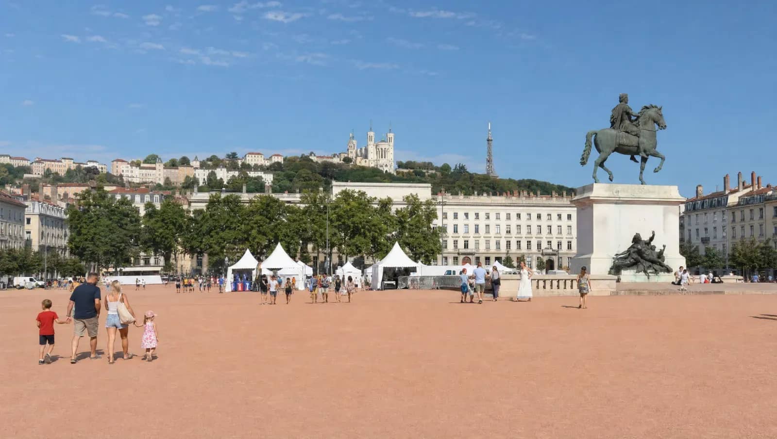 Place Bellecour à Lyon un matin d'été, stands blancs du Village défense et basilique de Fourvière en arrière-plan